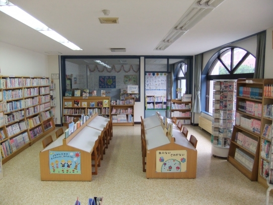 児童向け図書とお絵かきコーナー。机の奥に見えるガラス窓のついた空間が児童室。